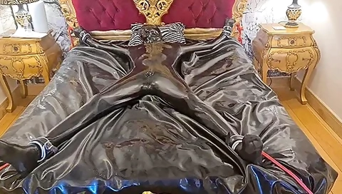 Latex-encased Woman Tied To Bed
